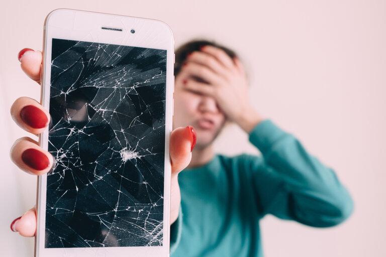 Zerbrochenes Glas, Bildschirm Smartphone, in der Hand eines verärgerten Mädchens