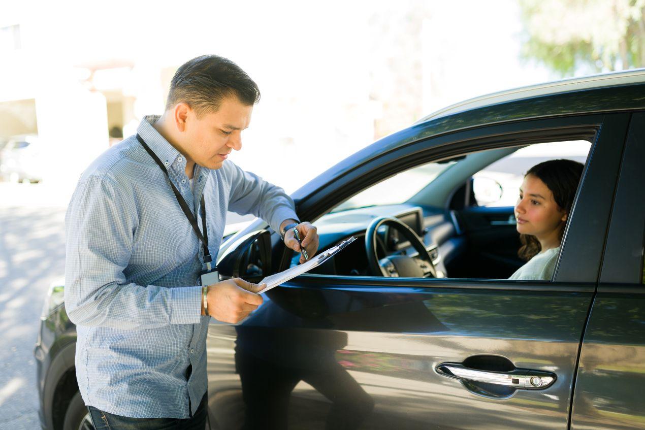 Ein Fahrlehrer gibt einer Teilnehmerin im Auto schriftliches Feedback während eines Fahrsicherheitskurses in Zürich.