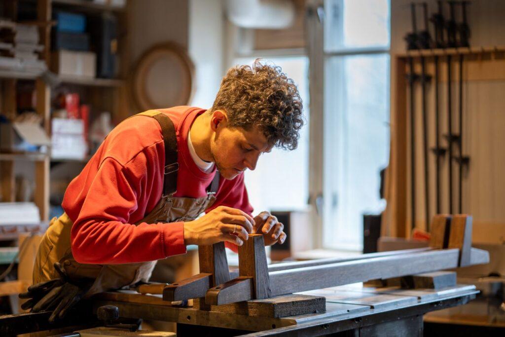 Tischler bei präziser Holzverarbeitung in einer Werkstatt in Potsdam – Möbelbau Potsdam mit Fokus auf Detailtreue und Handwerkskunst