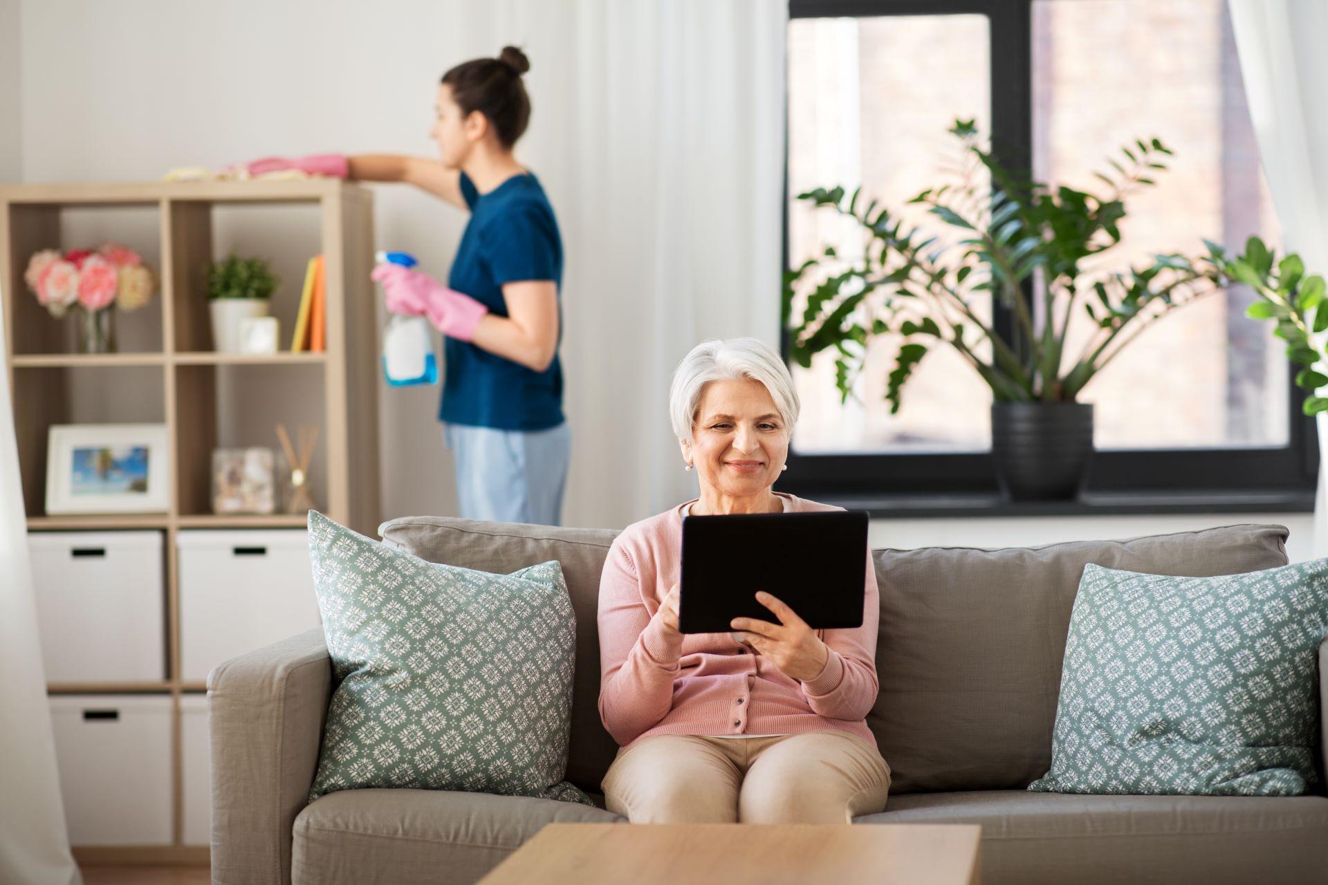 Seniorin entspannt, während im Hintergrund geputzt wird