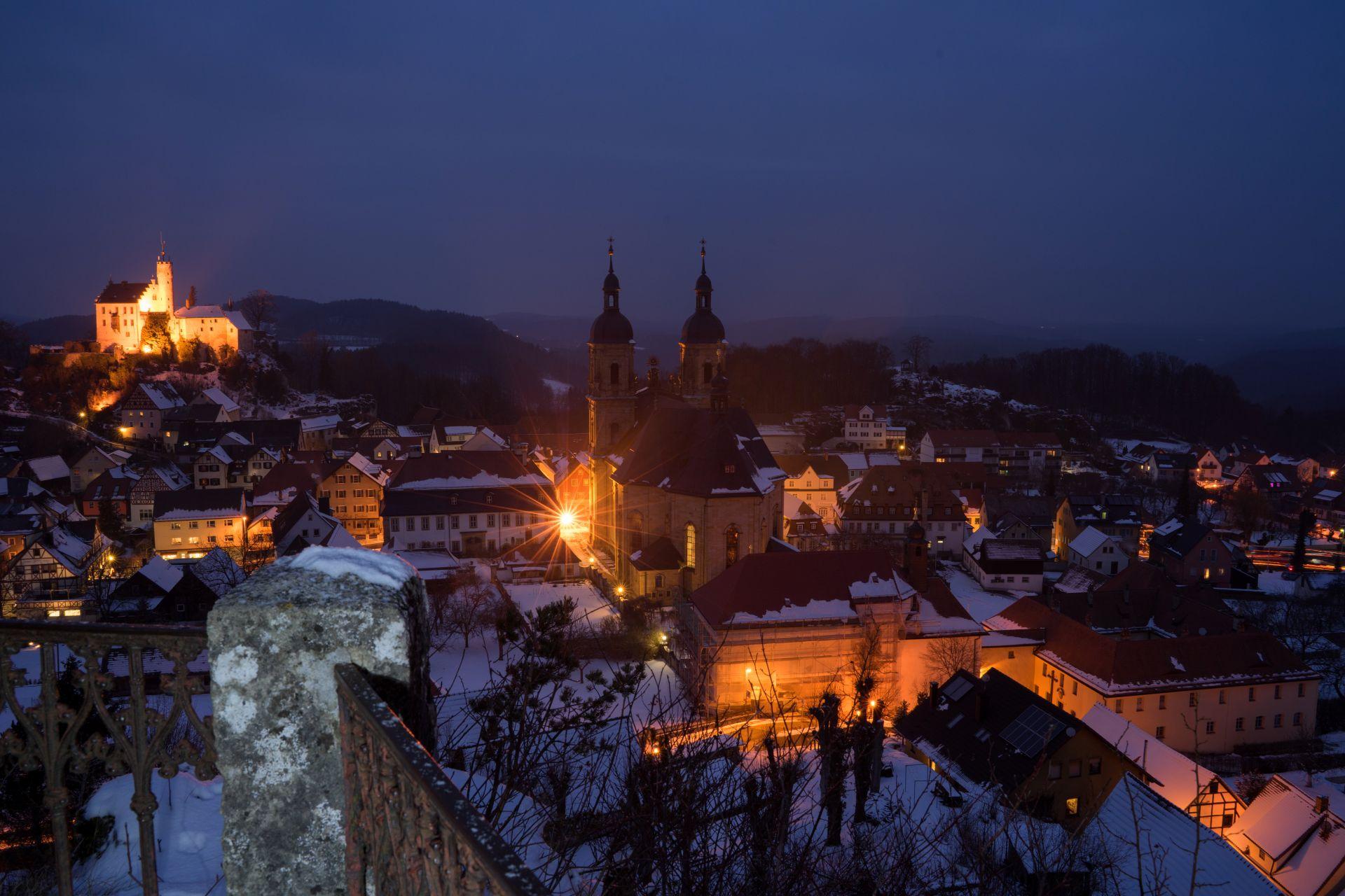 Winterabend in Goessweinstein in der Fraenkischen Schweiz mit beleuchteter Basilika und verschneiten Dächern