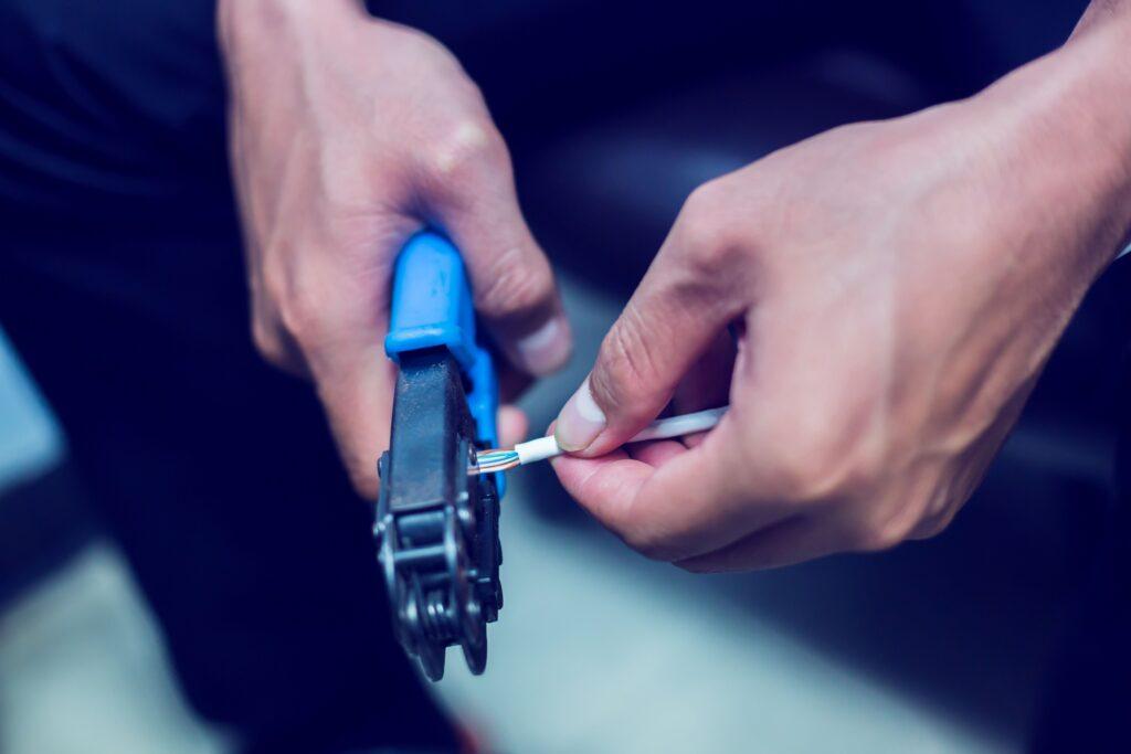 Hände beim Crimpen eines Kabels mit Zange – präzise Handarbeit in der Kabelkonfektion